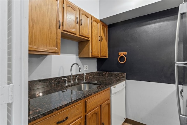 kitchen featuring sink, dark stone countertops, and dishwasher