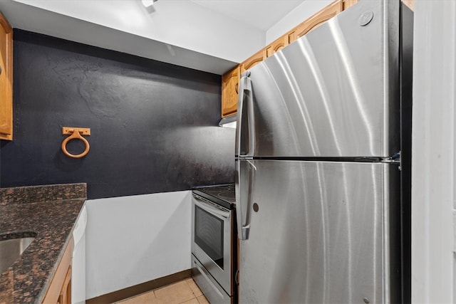 kitchen featuring dark stone countertops, light tile floors, and stainless steel appliances