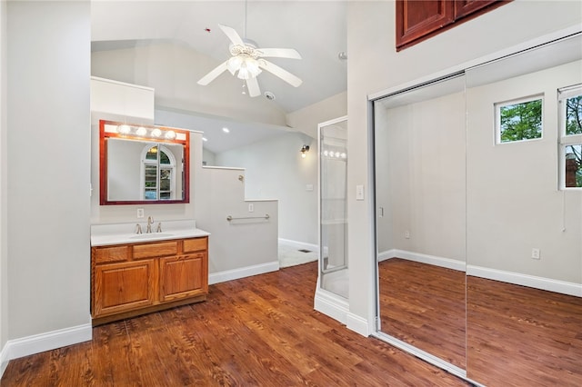 bathroom featuring ceiling fan, vanity with extensive cabinet space, lofted ceiling, a shower with shower door, and hardwood / wood-style flooring