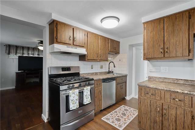 kitchen featuring dark hardwood / wood-style floors, sink, backsplash, ceiling fan, and stainless steel appliances