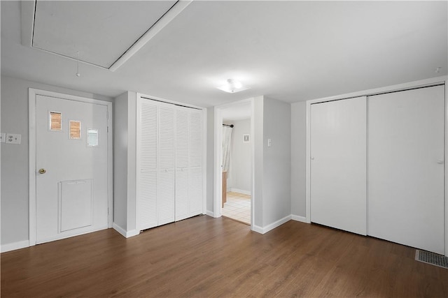 unfurnished bedroom with dark wood-type flooring and two closets