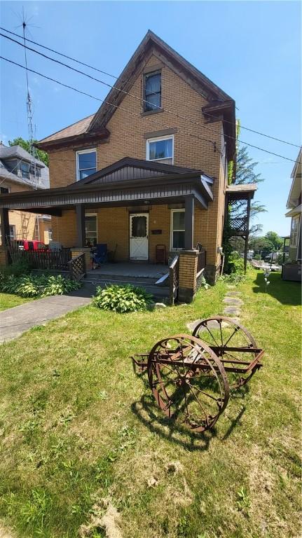 back of house with covered porch and a yard