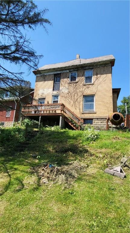 back of property featuring a deck and a yard