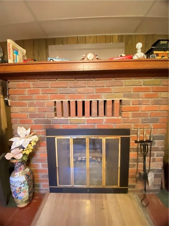 interior details with wood-type flooring, a brick fireplace, and wooden walls