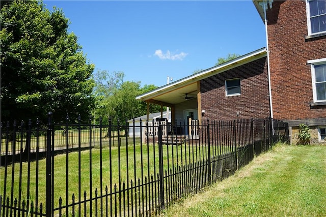 view of side of home with ceiling fan and a yard