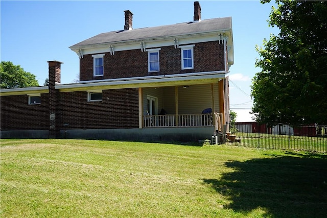 rear view of property featuring a lawn and a porch