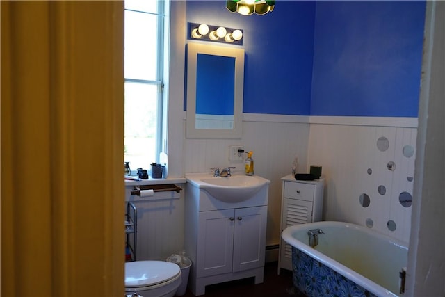 bathroom featuring a washtub, vanity, toilet, and a wealth of natural light