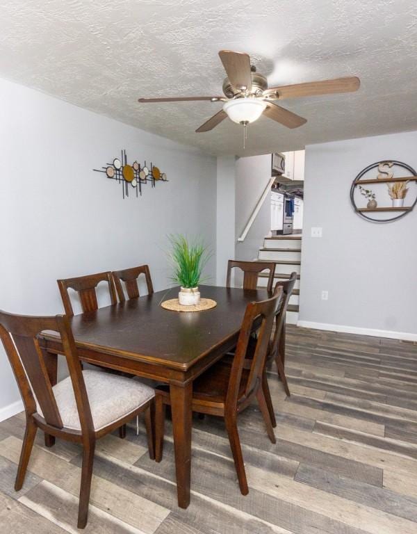 dining area featuring ceiling fan, wood-type flooring, and a textured ceiling