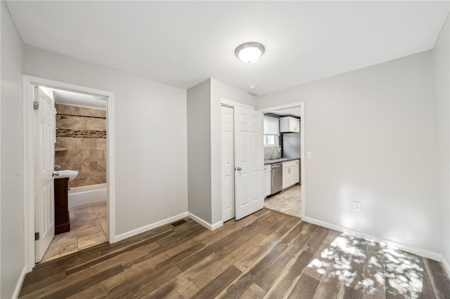 unfurnished bedroom with ensuite bath, sink, dark hardwood / wood-style flooring, and a closet