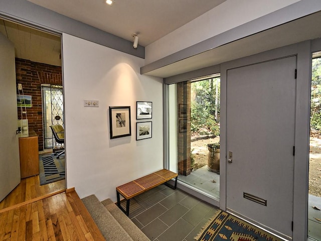 doorway to outside featuring brick wall and wood finished floors