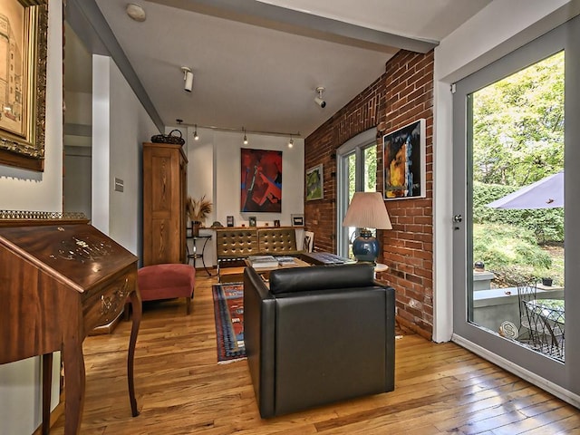 living room with track lighting, light wood-type flooring, and brick wall