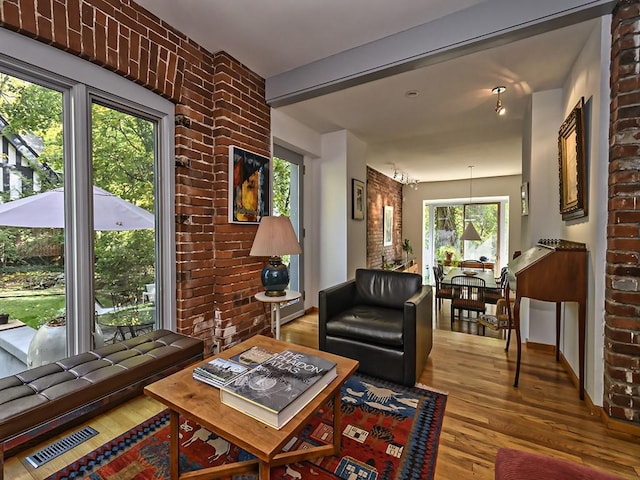 living area featuring visible vents, wood finished floors, and brick wall