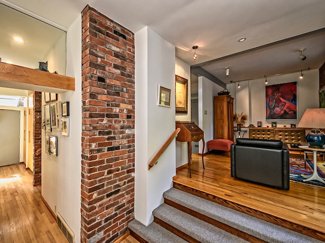 stairway with hardwood / wood-style flooring and brick wall