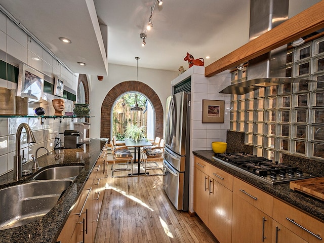 kitchen with backsplash, light wood-type flooring, track lighting, appliances with stainless steel finishes, and sink