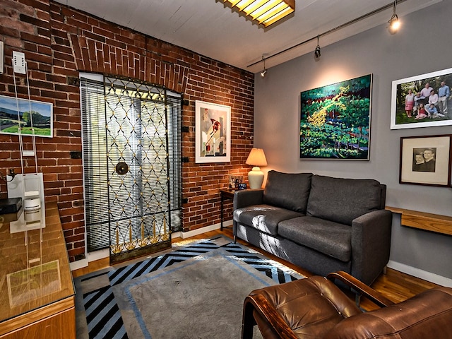 living room featuring brick wall, hardwood / wood-style flooring, and rail lighting