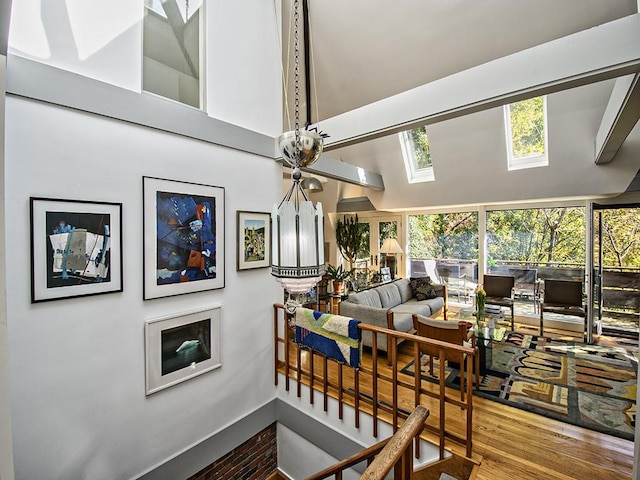 interior space with a towering ceiling, wood finished floors, and a skylight