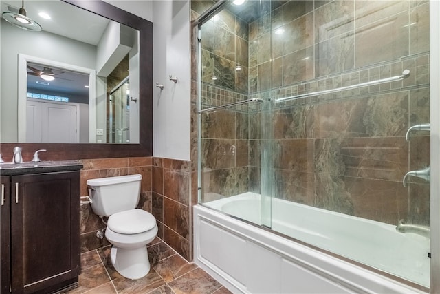 full bathroom with tile walls, toilet, ceiling fan, tile flooring, and bath / shower combo with glass door