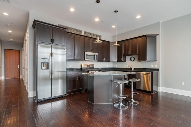 kitchen with dark hardwood / wood-style floors, stainless steel appliances, a kitchen island, and hanging light fixtures