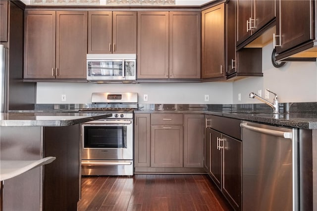 kitchen featuring sink, dark hardwood / wood-style floors, dark stone countertops, and stainless steel appliances