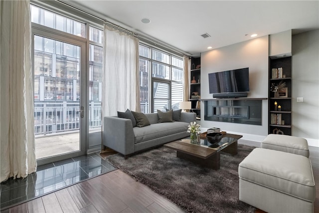 living room featuring built in shelves and wood-type flooring