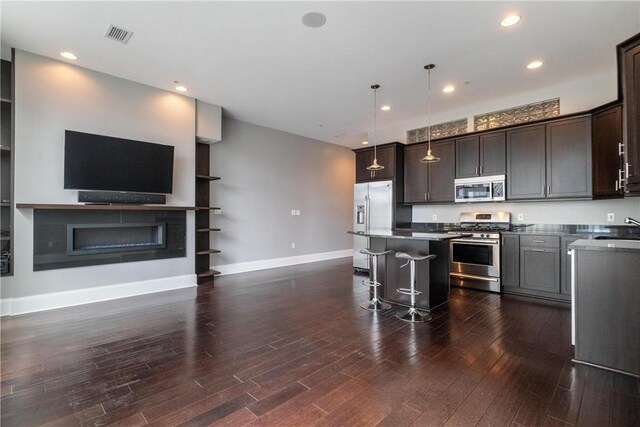 kitchen featuring dark brown cabinets, stainless steel appliances, dark wood-type flooring, hanging light fixtures, and a center island