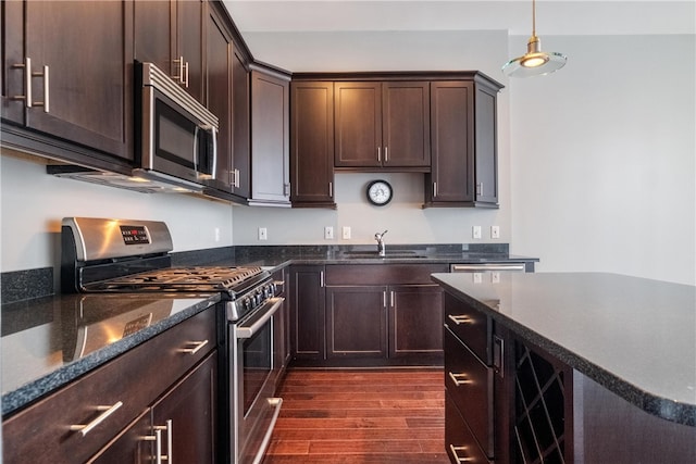 kitchen with dark hardwood / wood-style floors, dark brown cabinets, pendant lighting, and appliances with stainless steel finishes