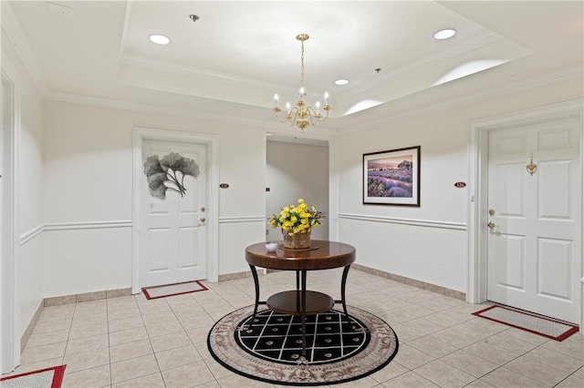 tiled entrance foyer with a notable chandelier, a tray ceiling, and ornamental molding