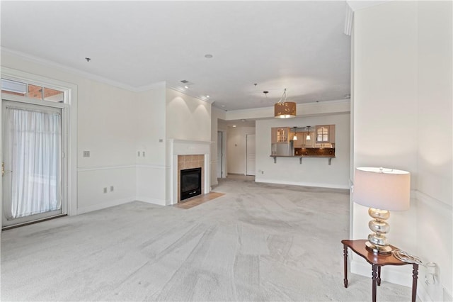 unfurnished living room with a tiled fireplace, light carpet, and ornamental molding