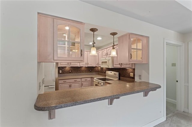 kitchen with white appliances, a breakfast bar area, and kitchen peninsula