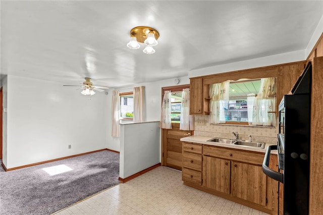 kitchen featuring light carpet, sink, tasteful backsplash, and ceiling fan