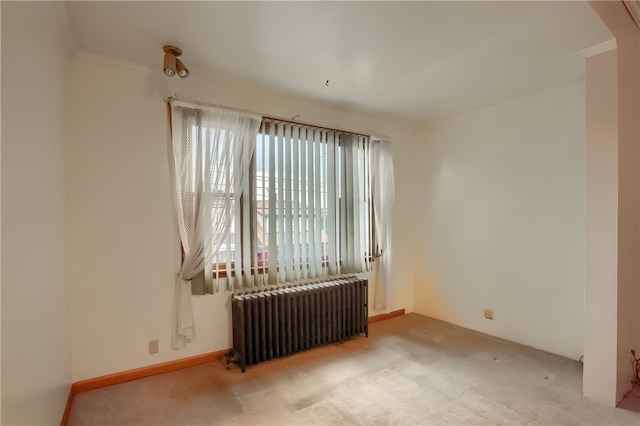 carpeted spare room featuring crown molding and radiator heating unit