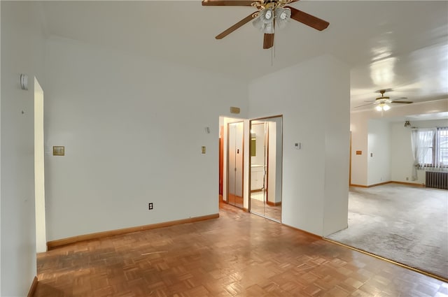 spare room with radiator heating unit, parquet floors, a high ceiling, and ceiling fan