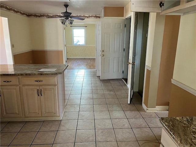 kitchen featuring cream cabinets, stone countertops, ceiling fan, and light tile patterned flooring