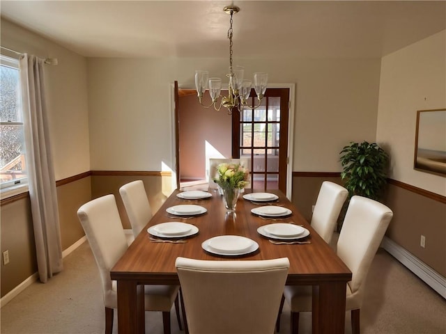 dining space featuring a notable chandelier, a healthy amount of sunlight, light colored carpet, and a baseboard radiator