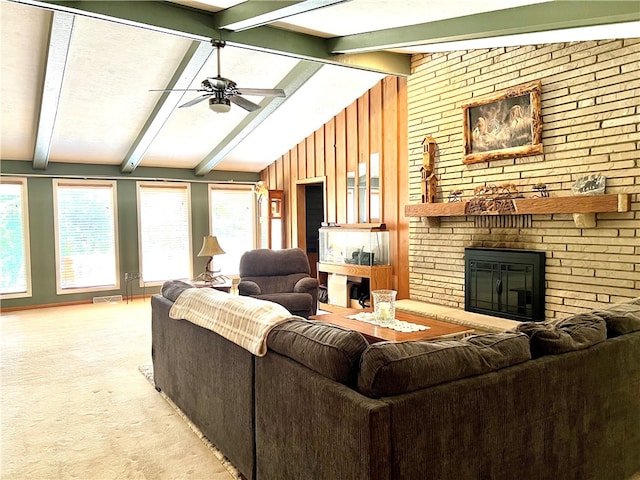 living room with wooden walls, vaulted ceiling with beams, ceiling fan, a fireplace, and light colored carpet