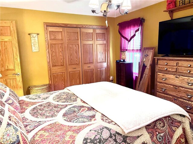 bedroom featuring ceiling fan with notable chandelier and a closet