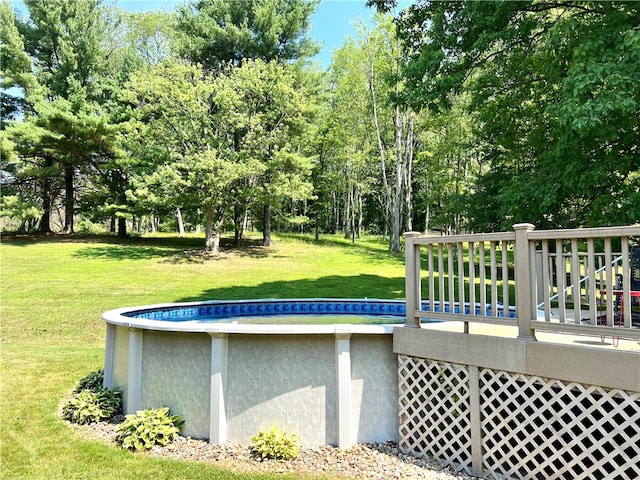 view of swimming pool with a yard and a deck