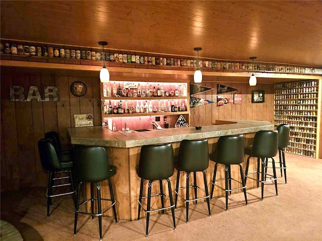 bar with wood walls, hanging light fixtures, carpet floors, and wood ceiling