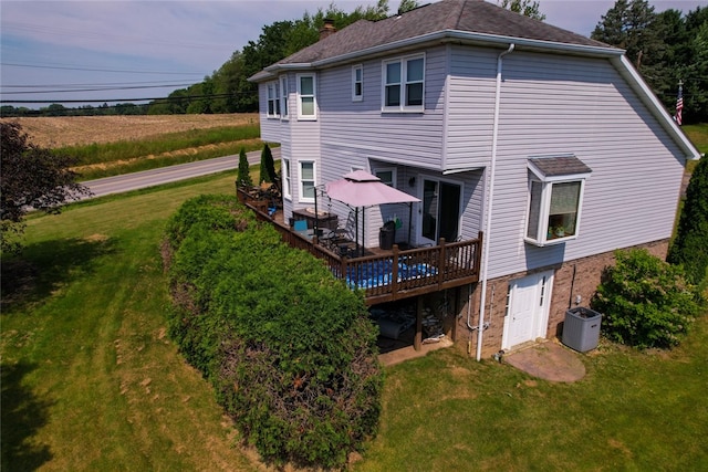 rear view of house with a wooden deck and a lawn