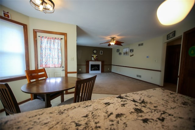 carpeted dining area with ceiling fan