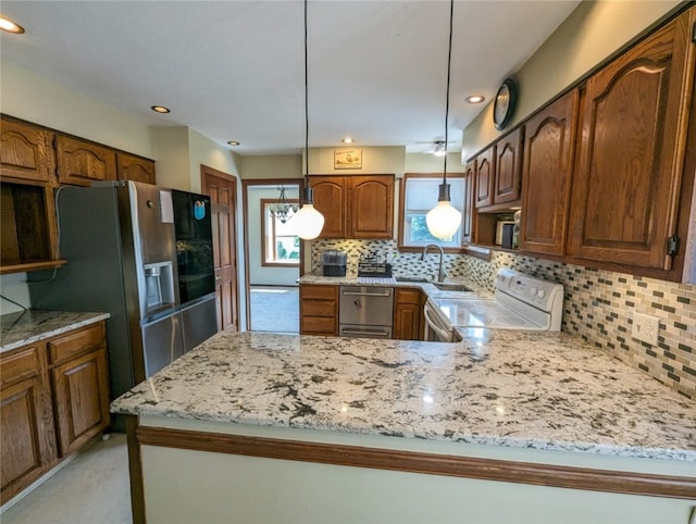 kitchen with decorative light fixtures, backsplash, light stone countertops, appliances with stainless steel finishes, and sink