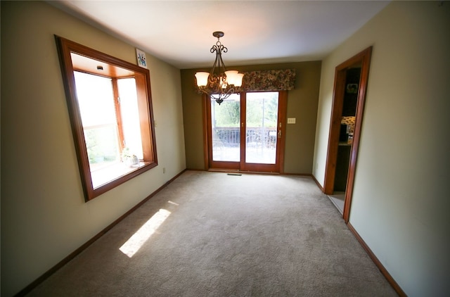 unfurnished dining area featuring carpet flooring and an inviting chandelier