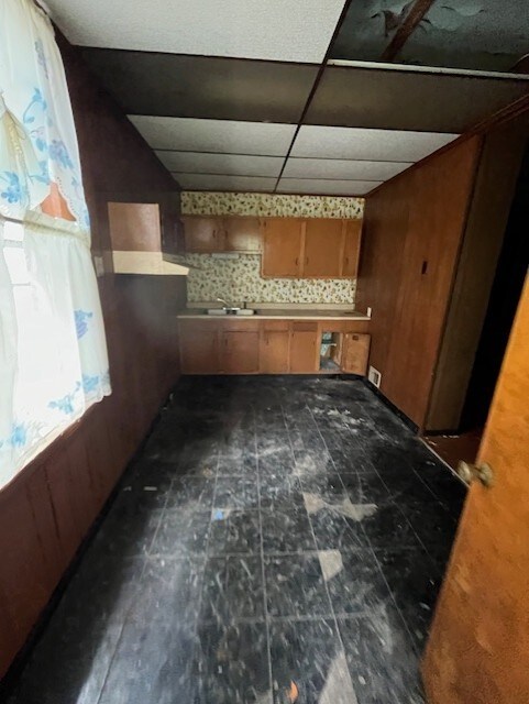 613 Center St, Versailles Boro, PA 15132 - kitchen featuring wooden walls, sink, and a drop ceiling