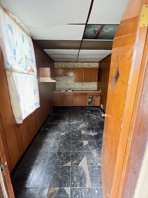 unfurnished living room featuring dark tile flooring and a drop ceiling