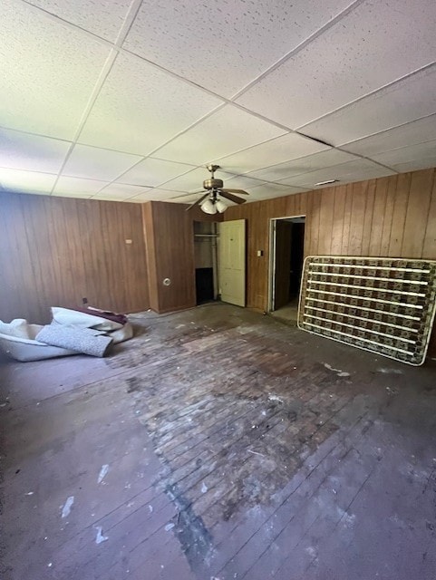 empty room with a drop ceiling, hardwood / wood-style floors, and wooden walls