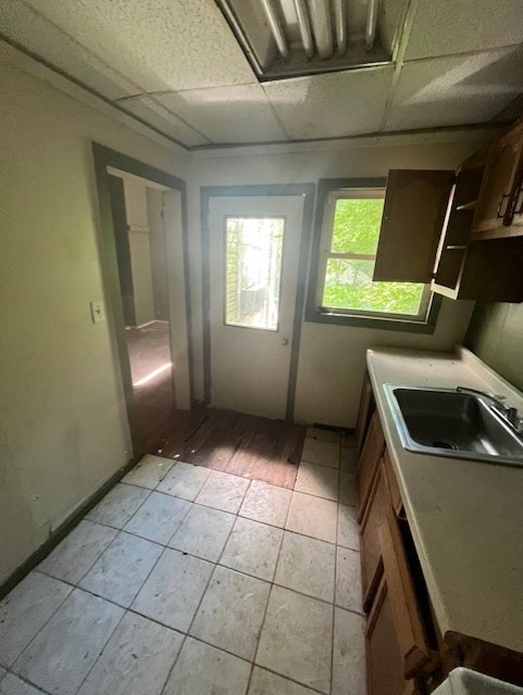 kitchen with light tile patterned flooring, a paneled ceiling, and sink