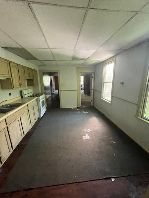 kitchen featuring a paneled ceiling, light brown cabinetry, sink, and gas range gas stove