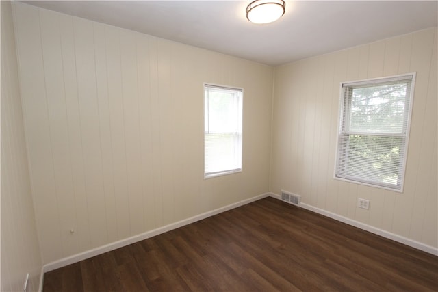 spare room with a wealth of natural light and dark wood-type flooring