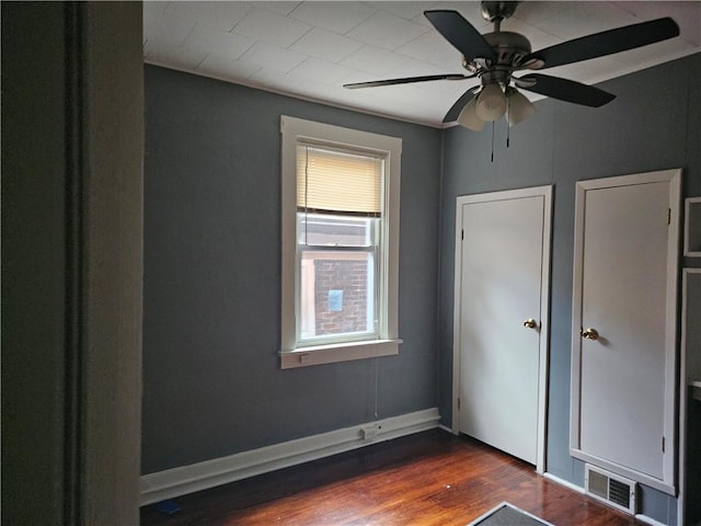 unfurnished bedroom featuring ceiling fan and dark hardwood / wood-style flooring