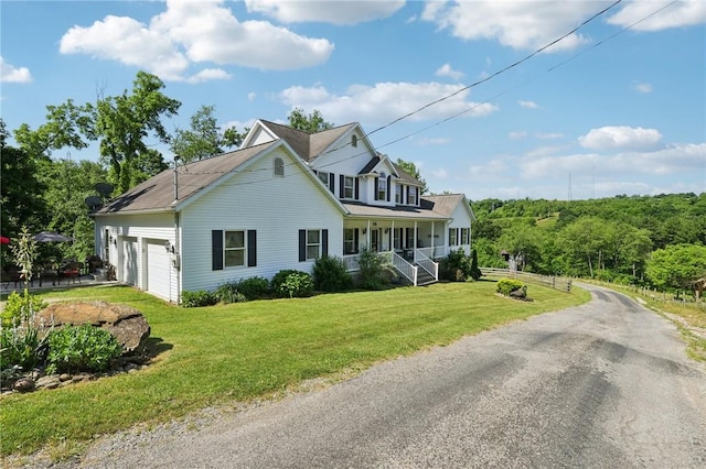 view of front of property featuring a garage, a porch, and a front lawn